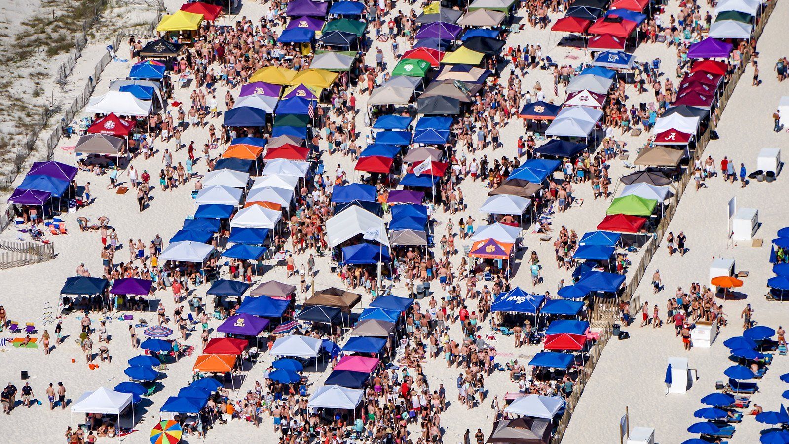 Aerial view of a crowded beach filled with many colorful pop-up tents and people.
