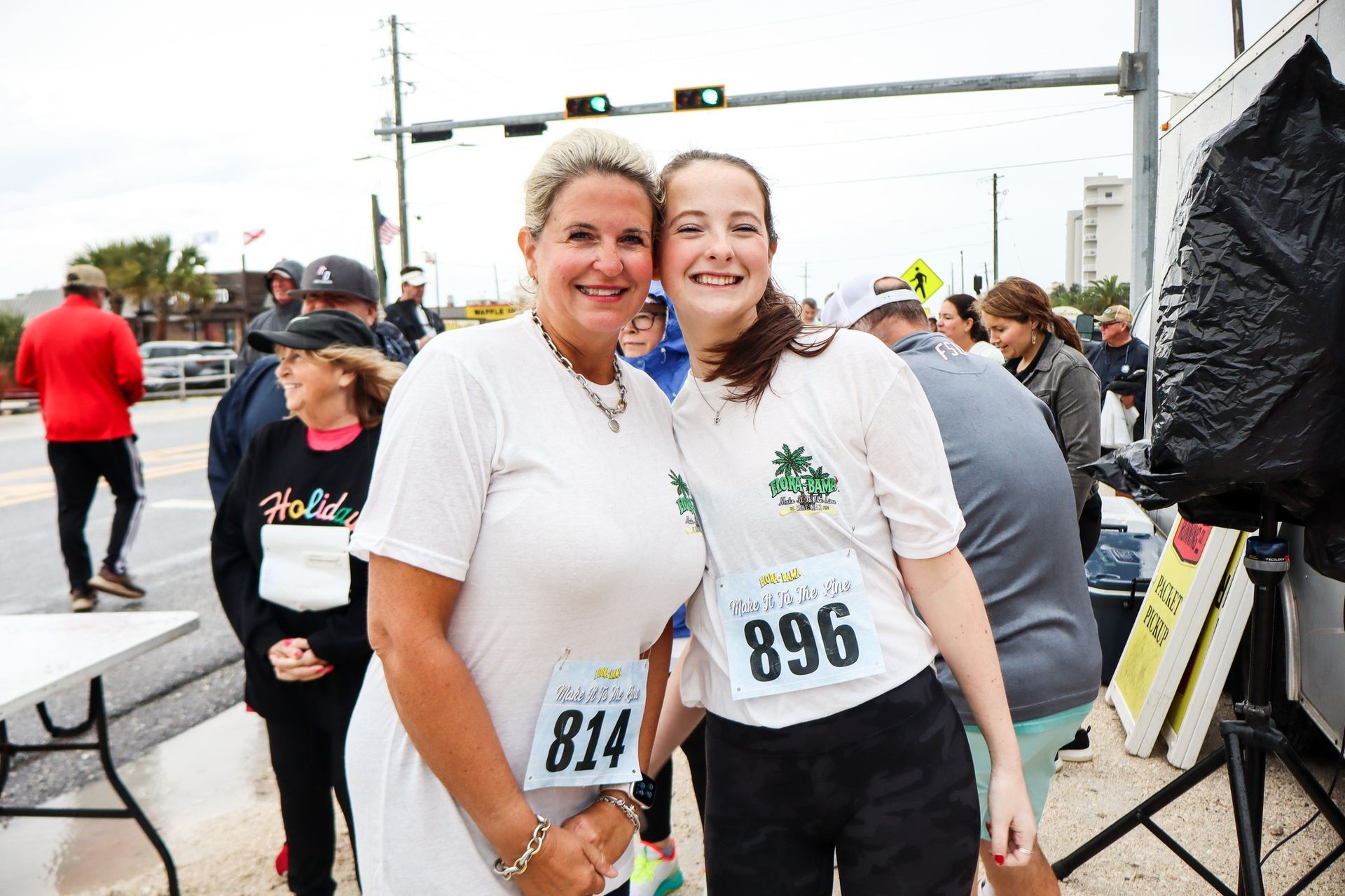 Two smiling runners with race bibs 814 and 896 pose together outside on a cloudy day.