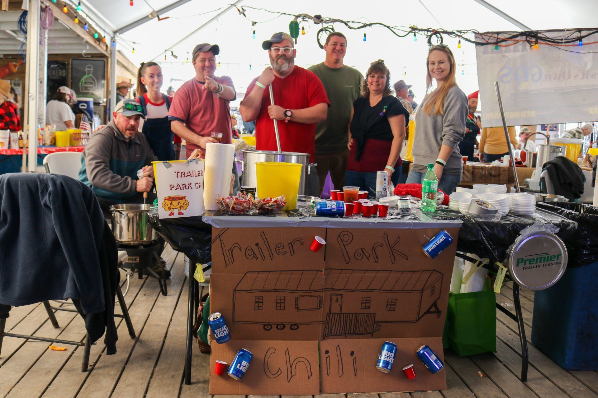 A group of people standing behind a table decorated with cans and red cups, labeled 