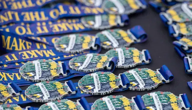 A collection of silver-toned athletic medals with blue ribbons inscribed with