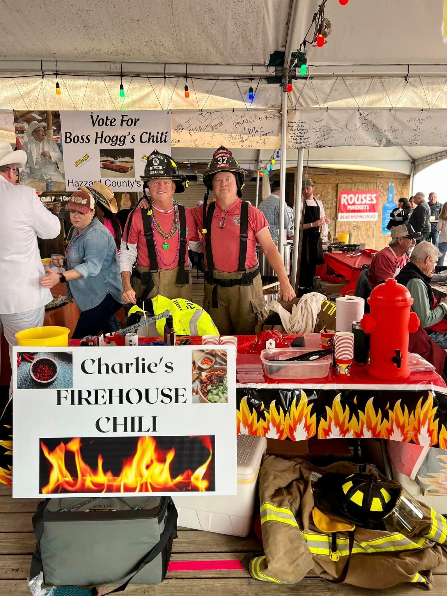 Two people wearing firefighter helmets stand behind a 