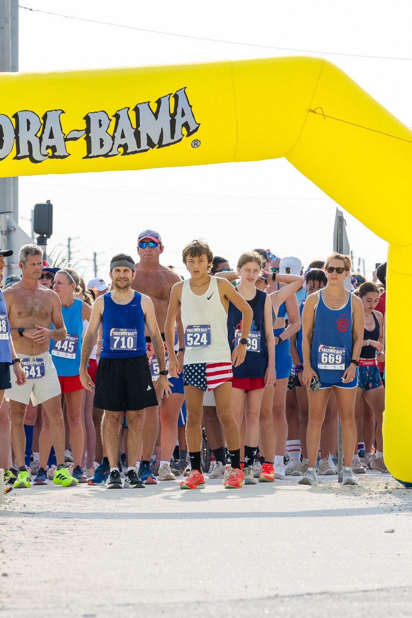 Runners stand at a starting line under a yellow inflatable 