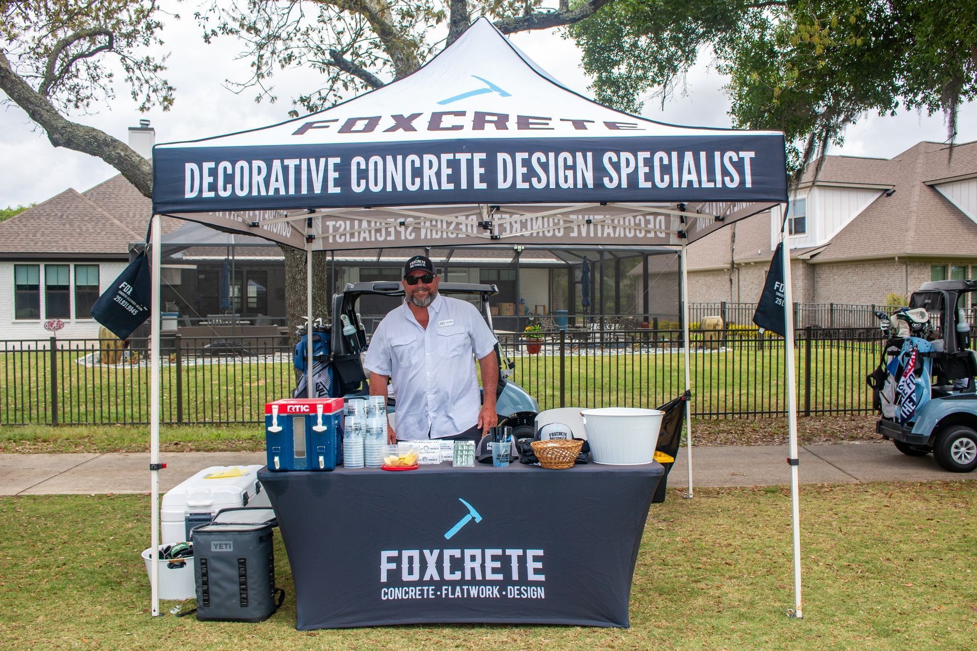 A Foxcrete promotional tent outdoors with a person standing behind a branded table displaying products.