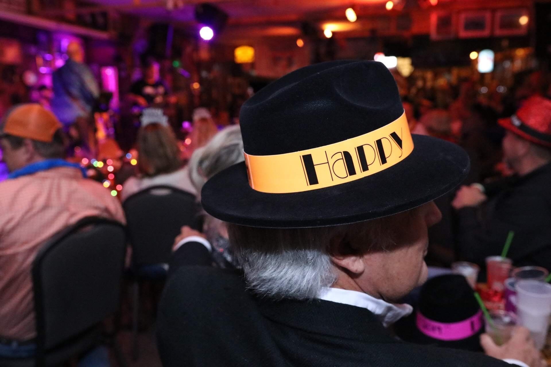 A person wears a black fedora with a yellow