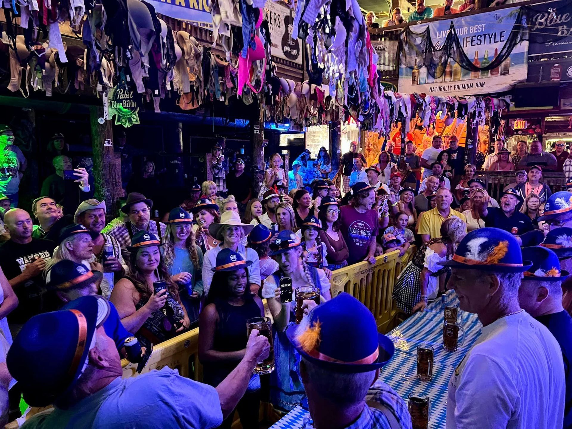 Crowd at a festive pub celebration with many hats hanging from the ceiling.