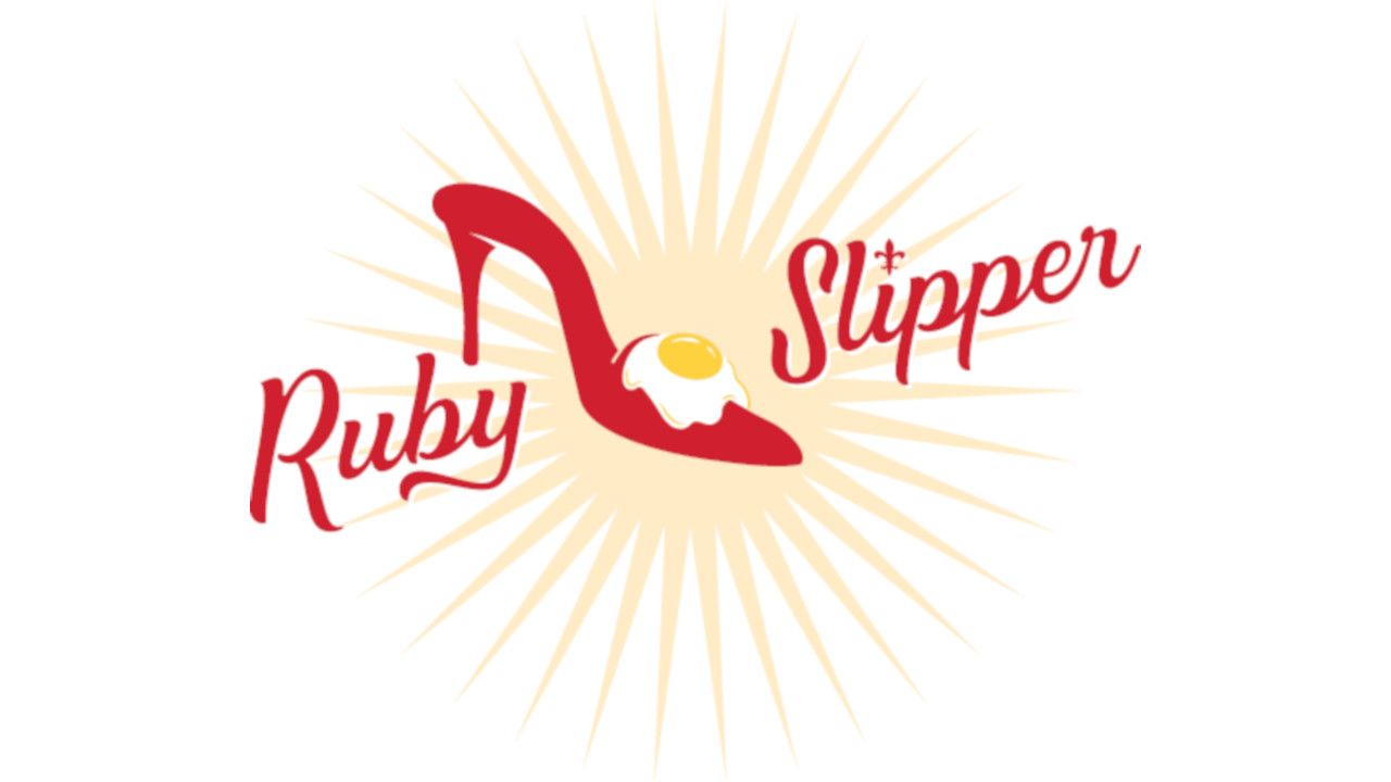 Logo for Ruby Slipper featuring red high-heeled shoe with an egg yolk on top, surrounded by sunburst rays.