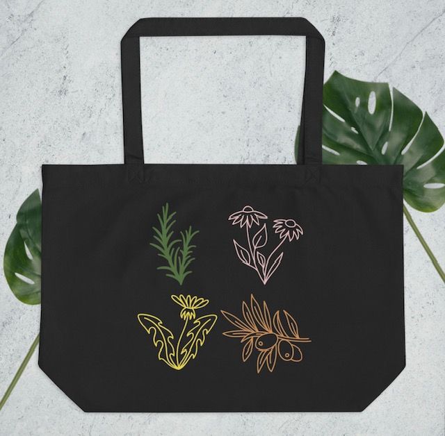Black tote bag with colorful line drawings of rosemary, coneflowers, a dandelion, and an olive branch.