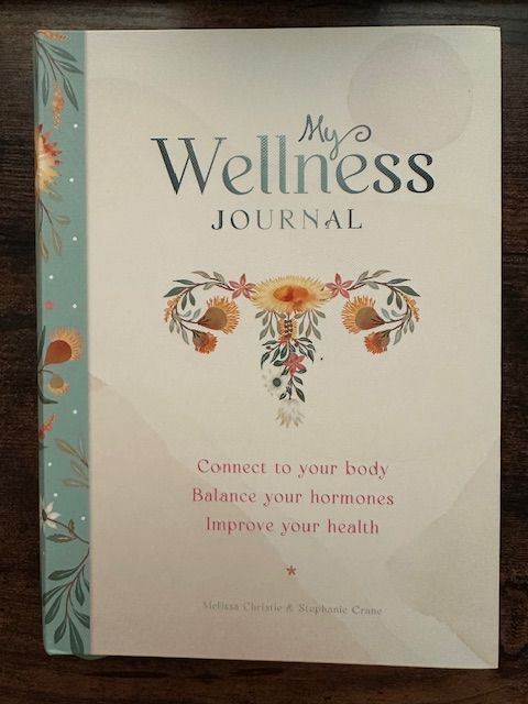 A wellness journal with floral uterus illustration; text reads