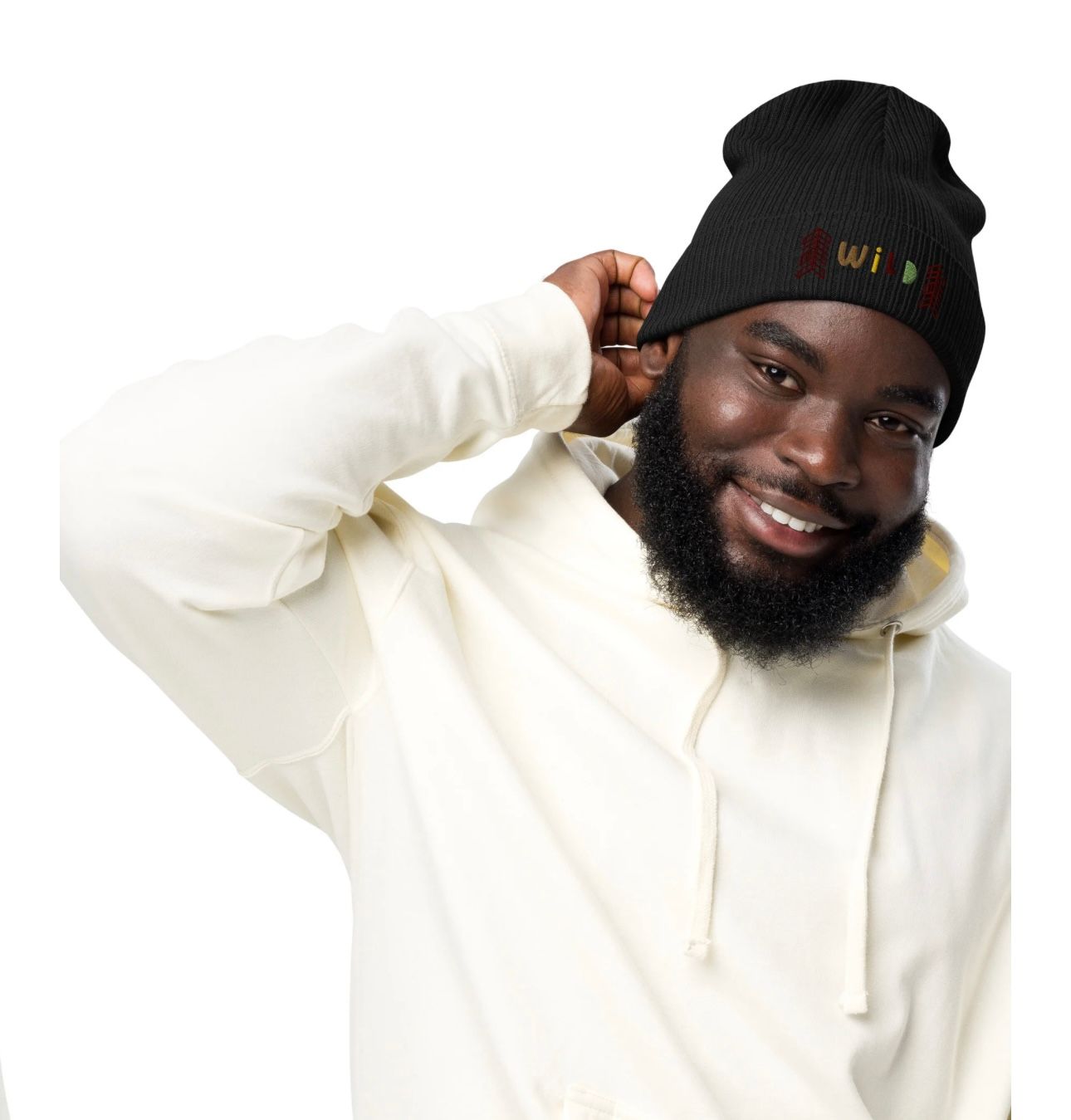 Man in black beanie and cream hoodie smiling, touching his hat.