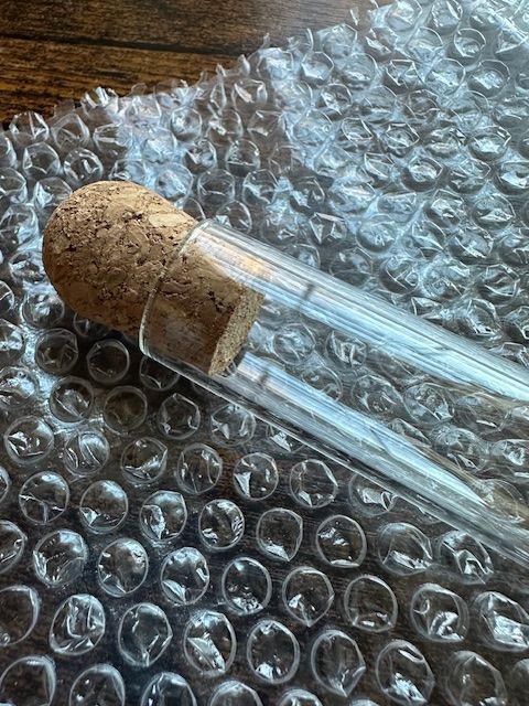 Two glass vials with cork stoppers rest on bubble wrap.