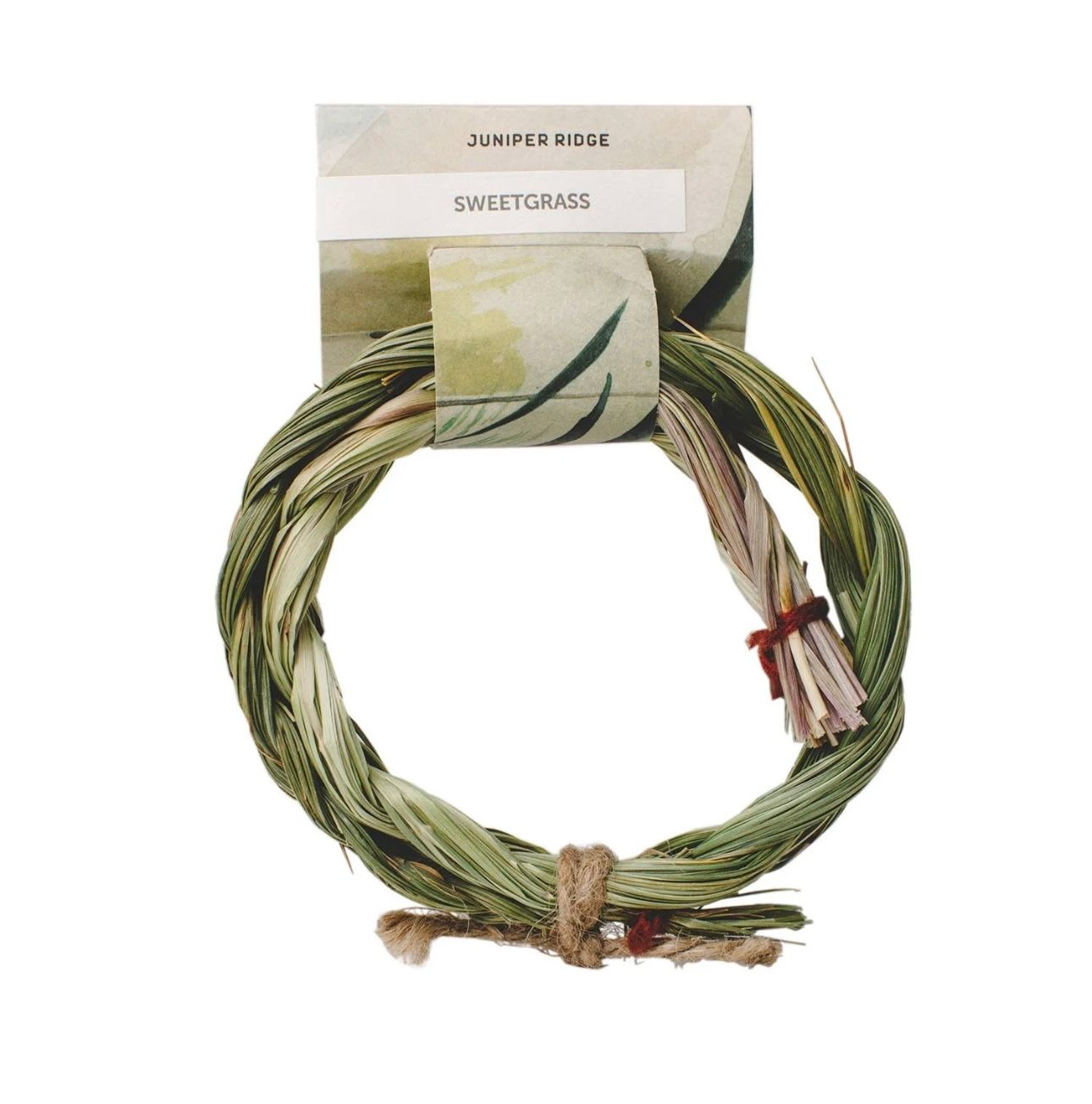 A woven sweetgrass wreath for small animals, with a paper tag.