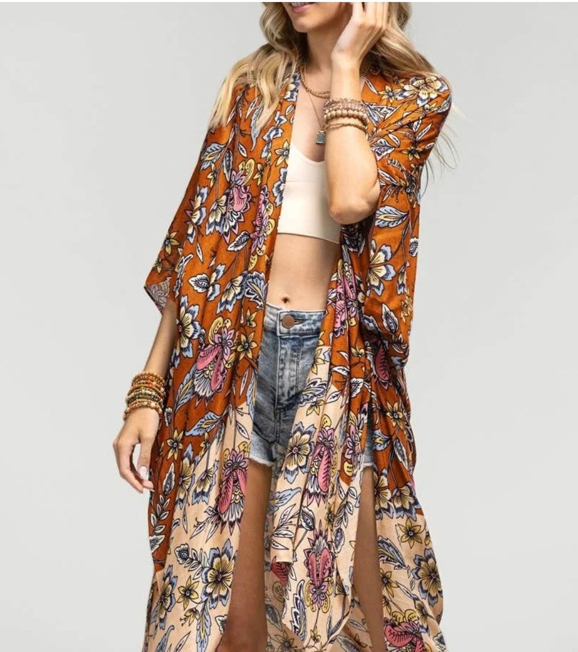Woman wearing a floral print kimono, shorts, and crop top; brown and beige colors.