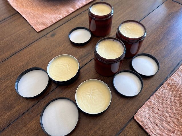 Brown jars of cream with open lids on a wooden table.