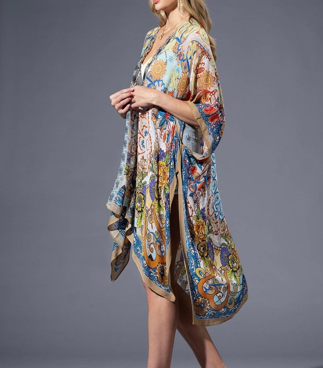 Woman in printed kimono-style cover-up, standing, in front of a gray backdrop.