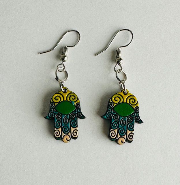 Pair of Hamsa hand earrings with turquoise, yellow, and green detailing, hanging from silver hooks.