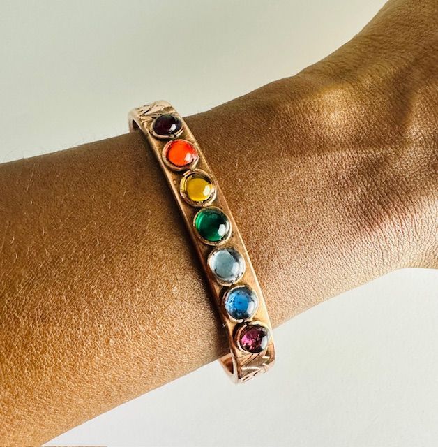 Copper bracelet with colorful gemstones, worn on a wrist.