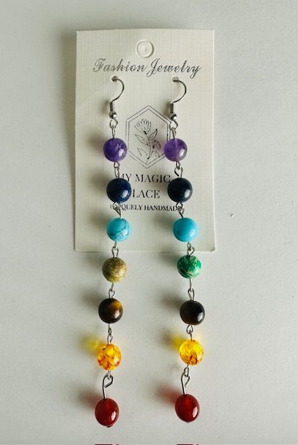 Earrings with colorful beads, arranged vertically in chakra colors, hanging from a card.