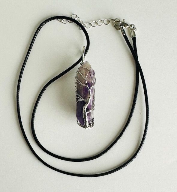 Amethyst crystal pendant necklace with black cord.