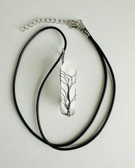 Clear quartz crystal pendant necklace on black cord.