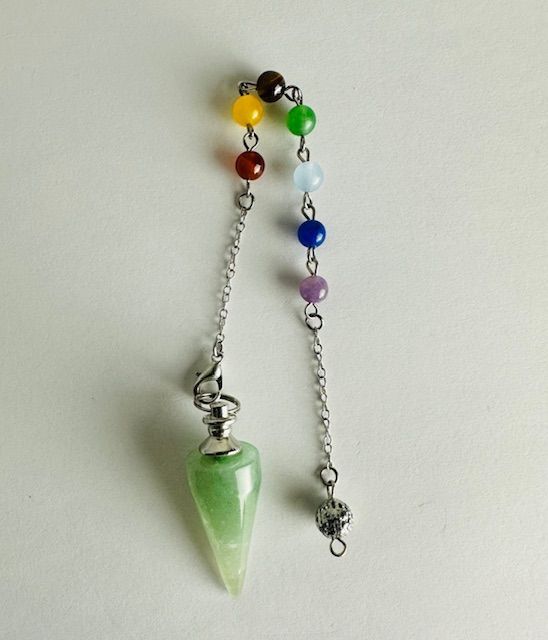 Green crystal pendulum with seven chakra colored beads on a silver chain, against a white background.