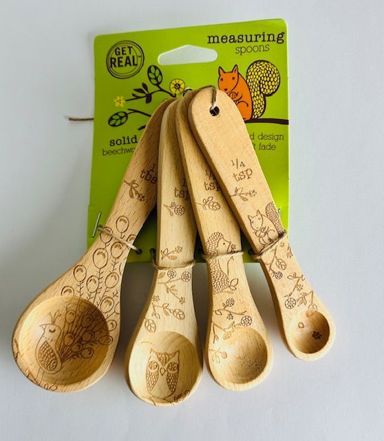 Set of four wooden measuring spoons with etched designs and a green tag.
