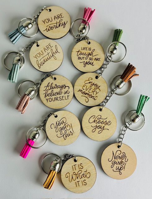 Wooden keychains with motivational phrases and colorful tassels.