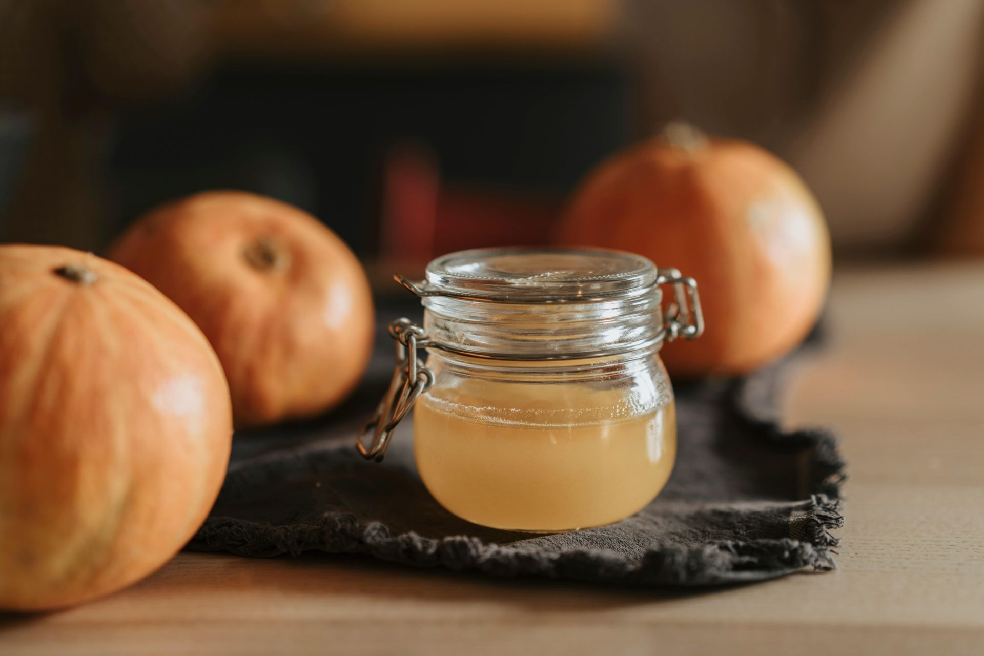 Jar of liquid with apples on a dark cloth, wooden table background.