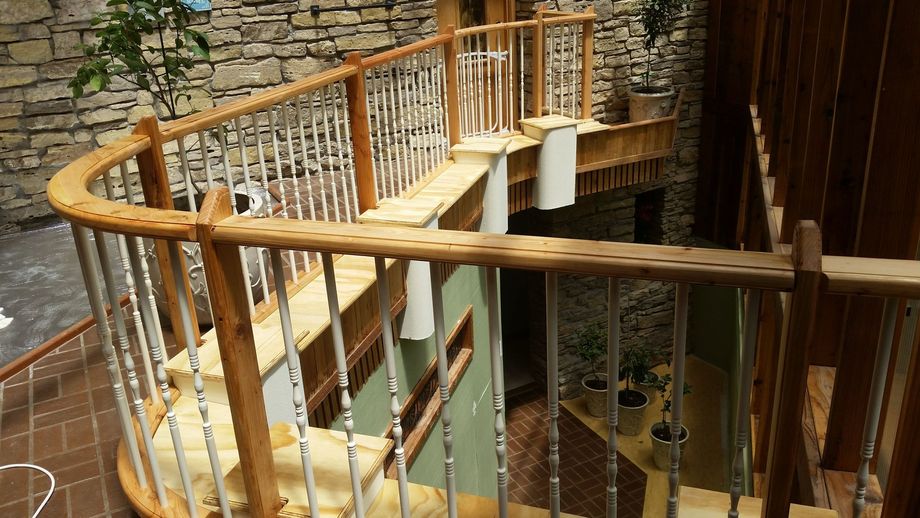 Curved wooden staircase with metal railings in an indoor atrium