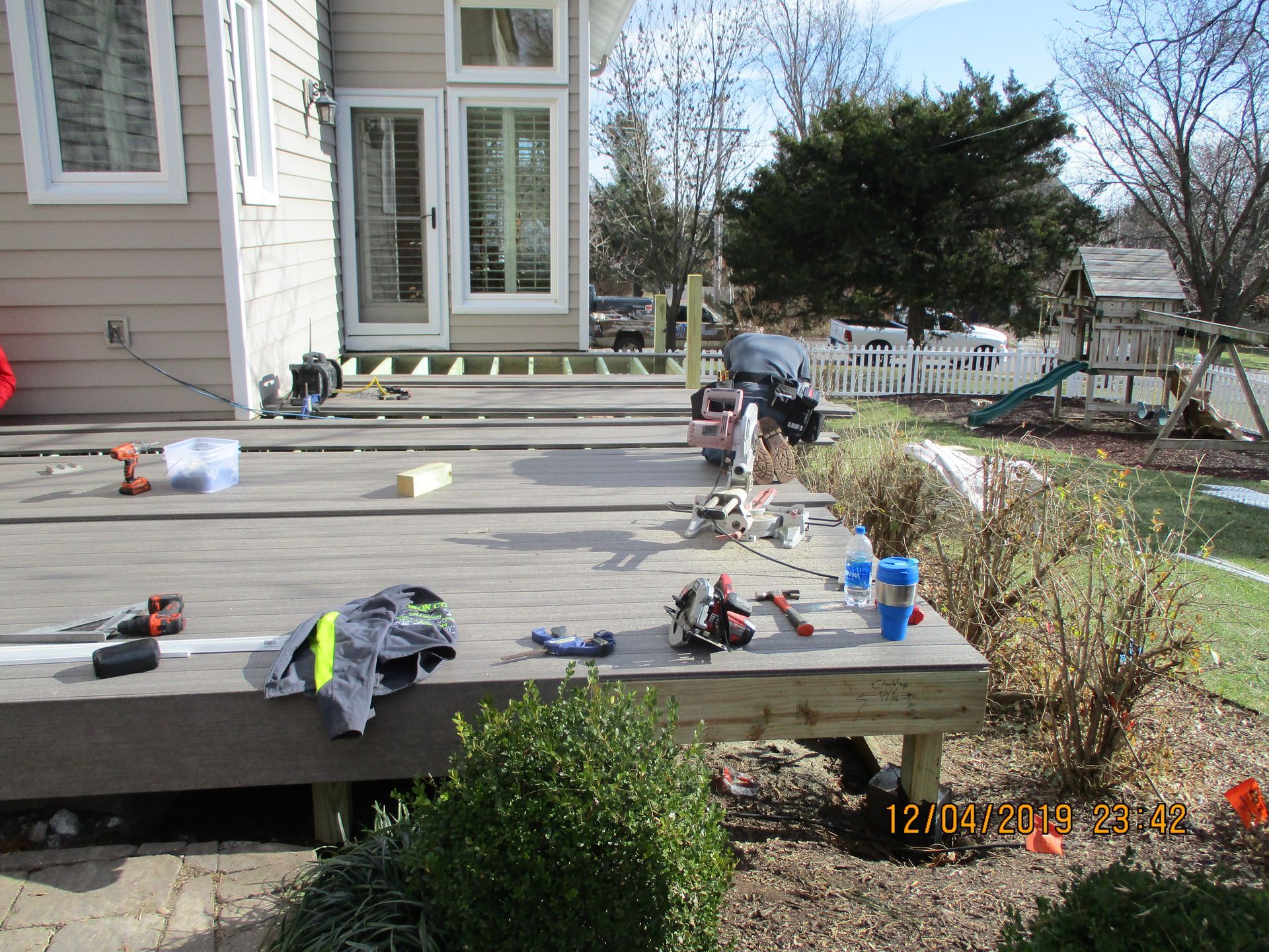 Backyard deck under construction with tools and supplies outside a house