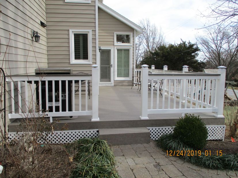 House back deck with white railings, ramp, and steps leading to a patio door