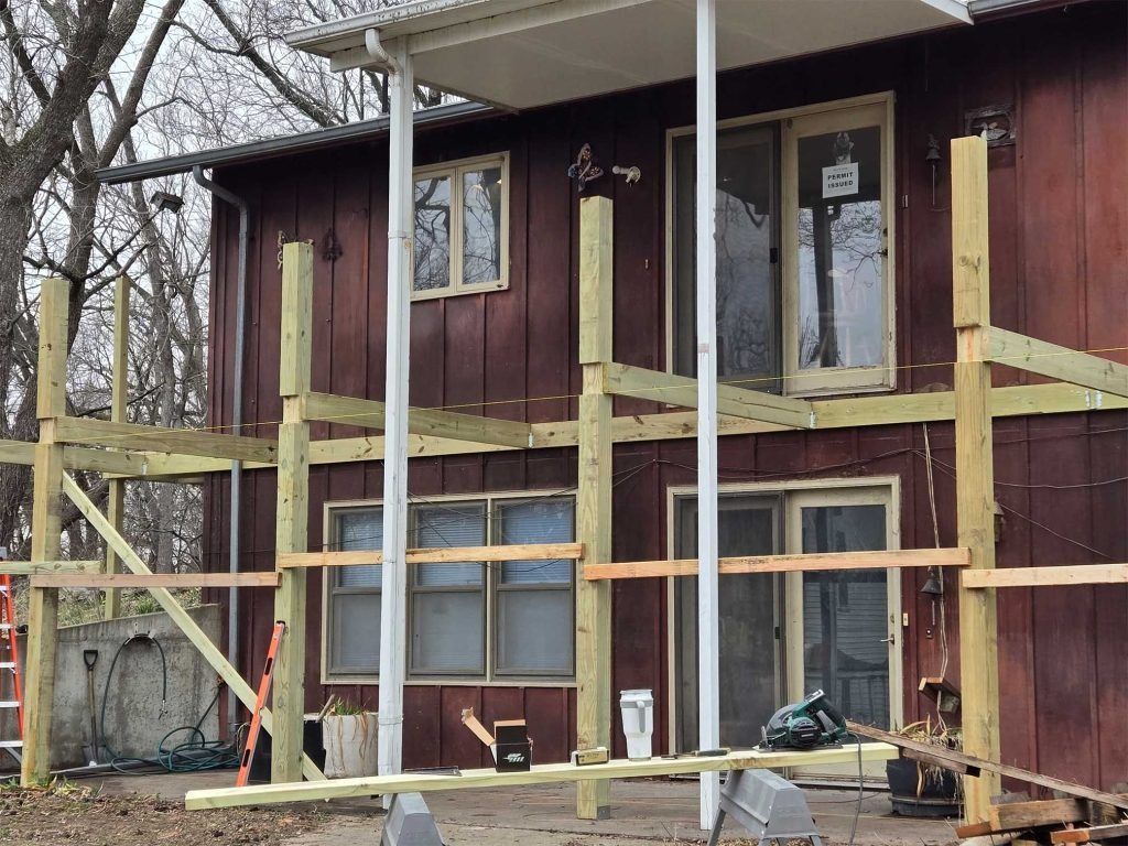 Wooden house under renovation with scaffolding and exposed framing on the front porch