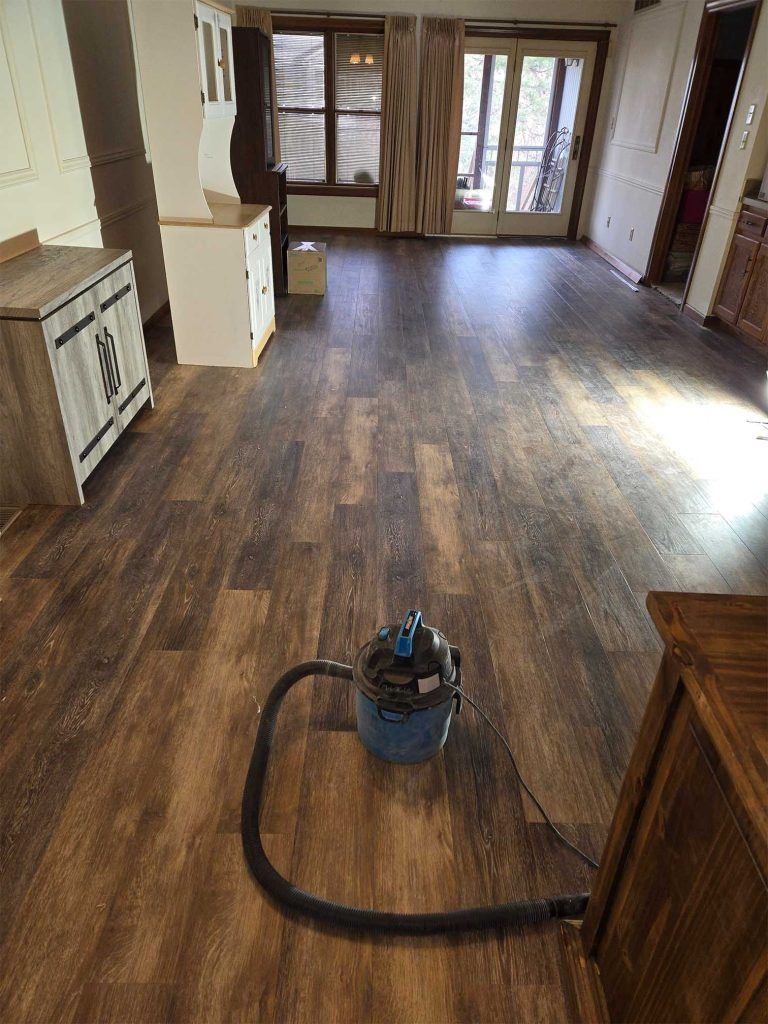 Vacuum cleaner on a hardwood floor in an empty living room with sliding glass doors