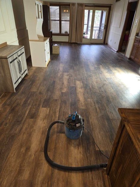 Vacuum cleaner on a dark wood floor in a mostly empty room with French doors.