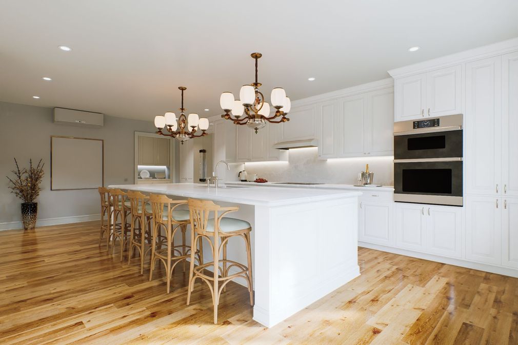 Bright white kitchen with island, barstools, wood floors, and two pendant chandeliers