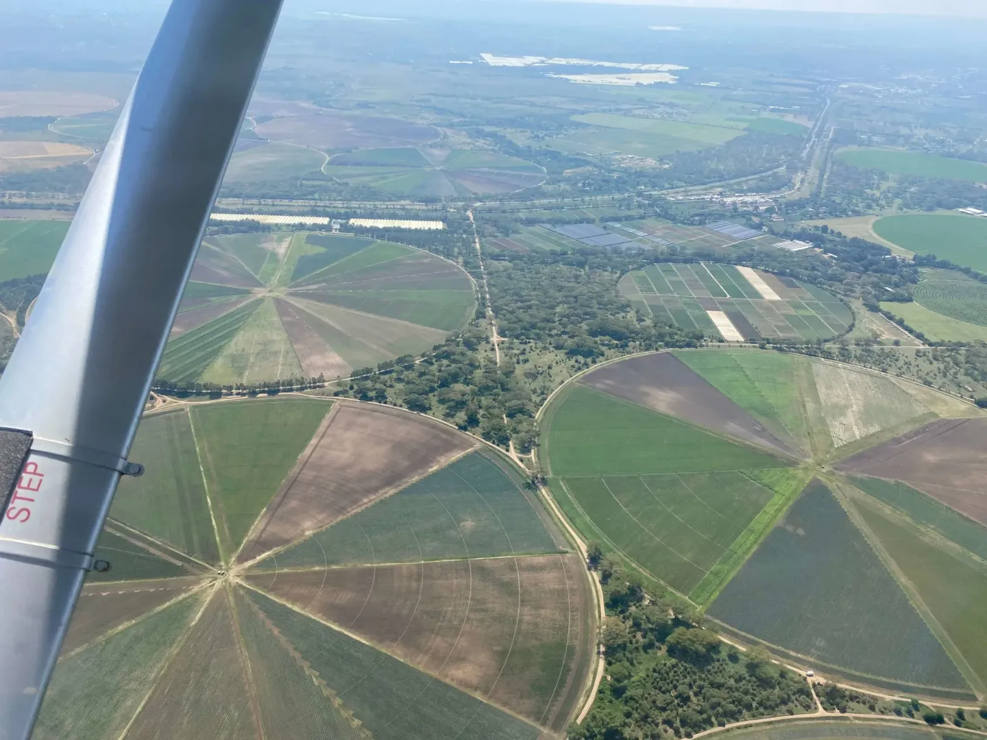 A plane is flying over a lush green field