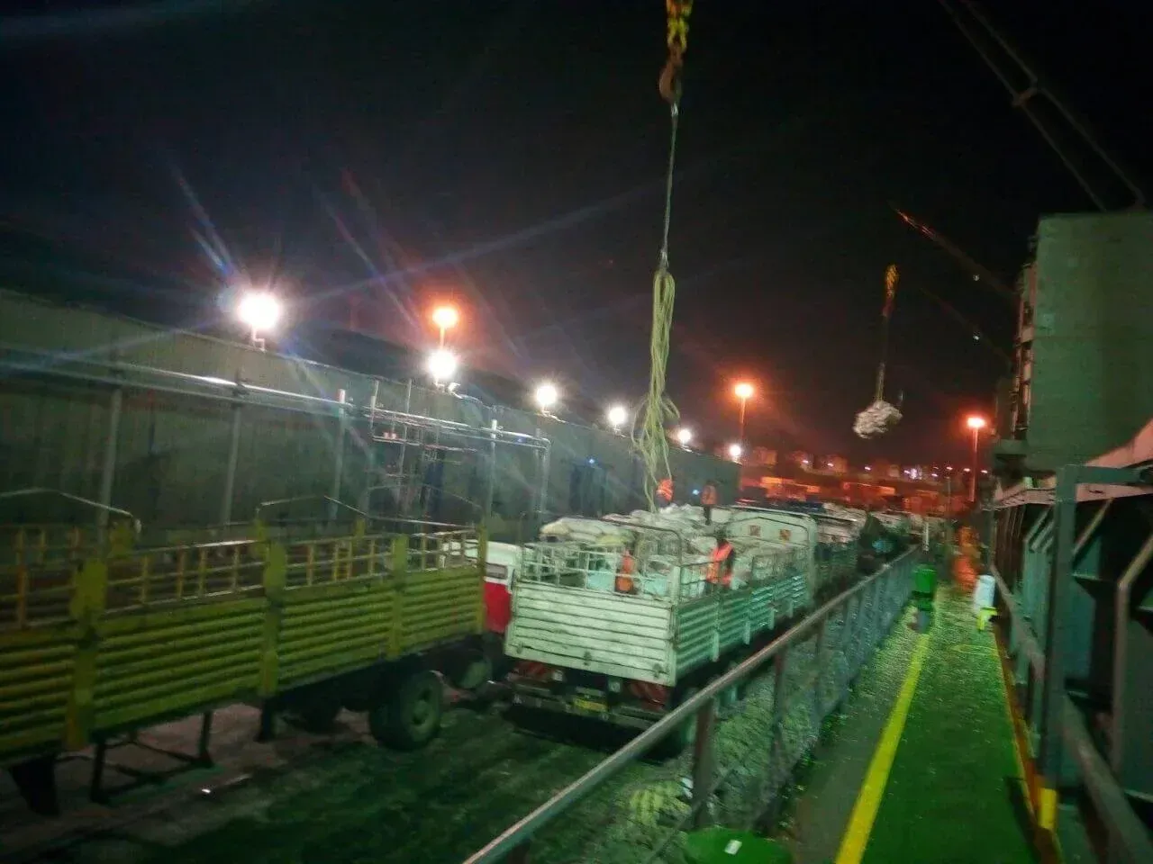 A truck is being lifted by a crane at night