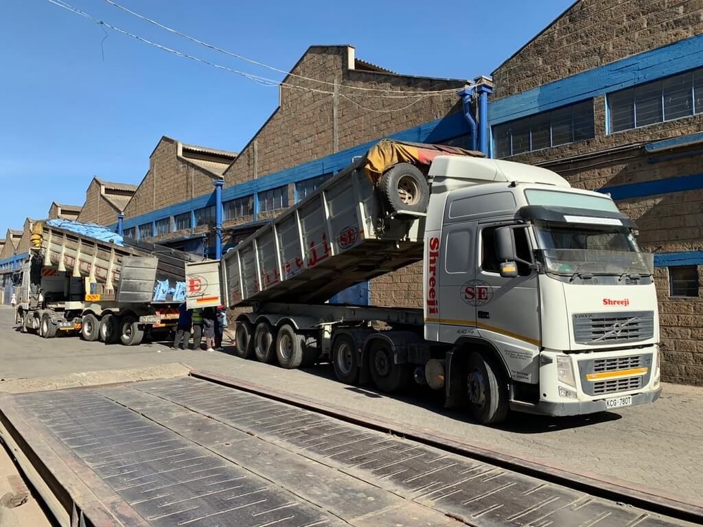 A truck is being weighed on a scale in front of a building.