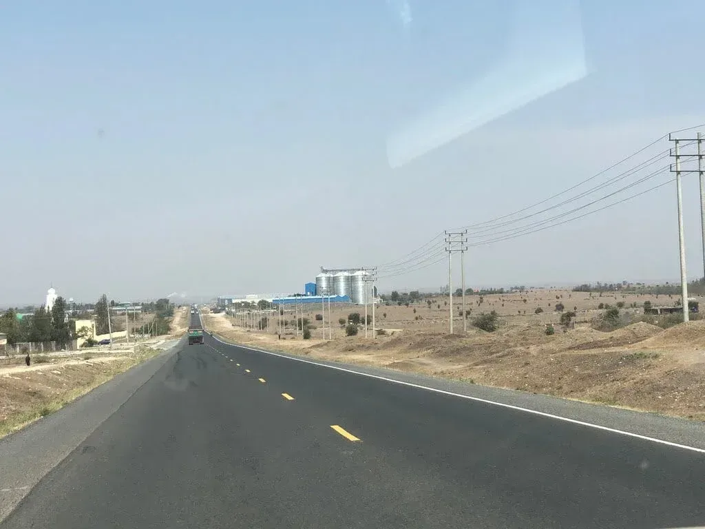 A car is driving down a highway in the desert.