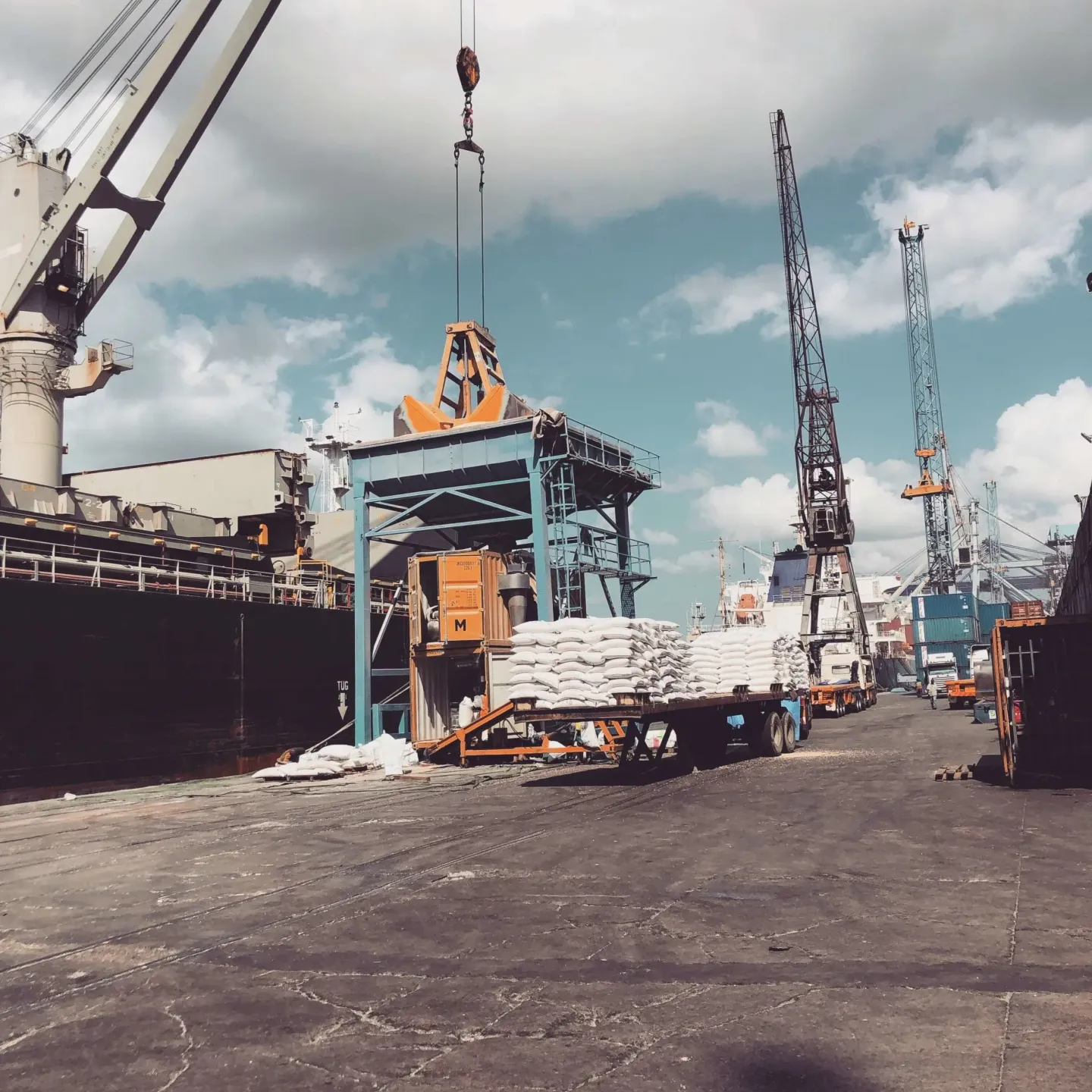 A large ship is being loaded with cargo by a crane