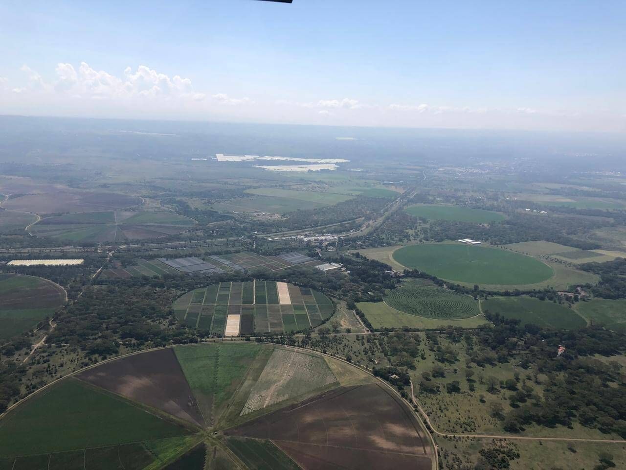 An aerial view of a lush green landscape with lots of fields and trees.