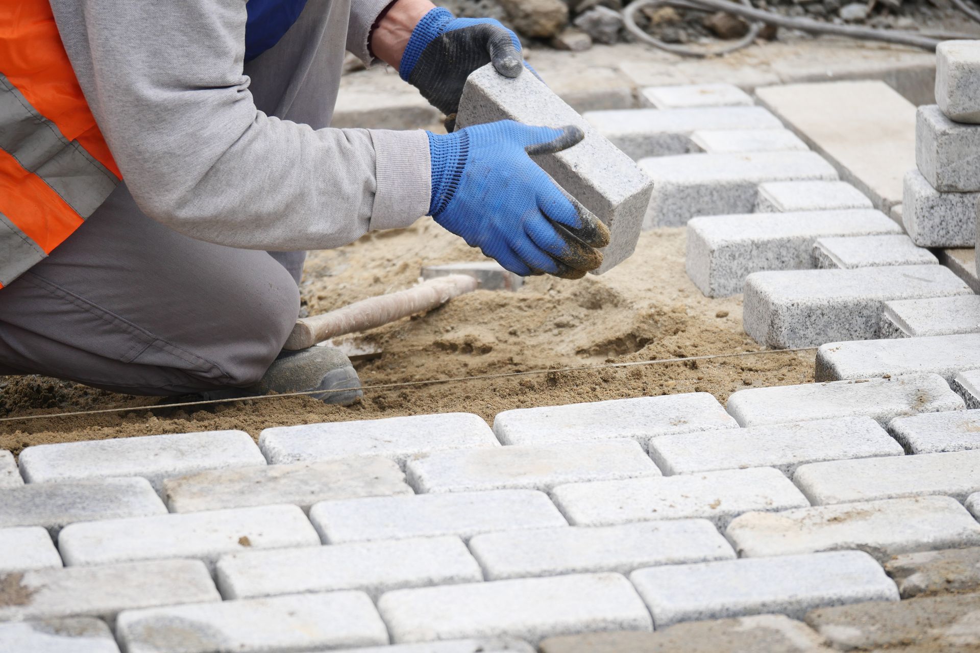 A man is laying bricks on a sidewalk.