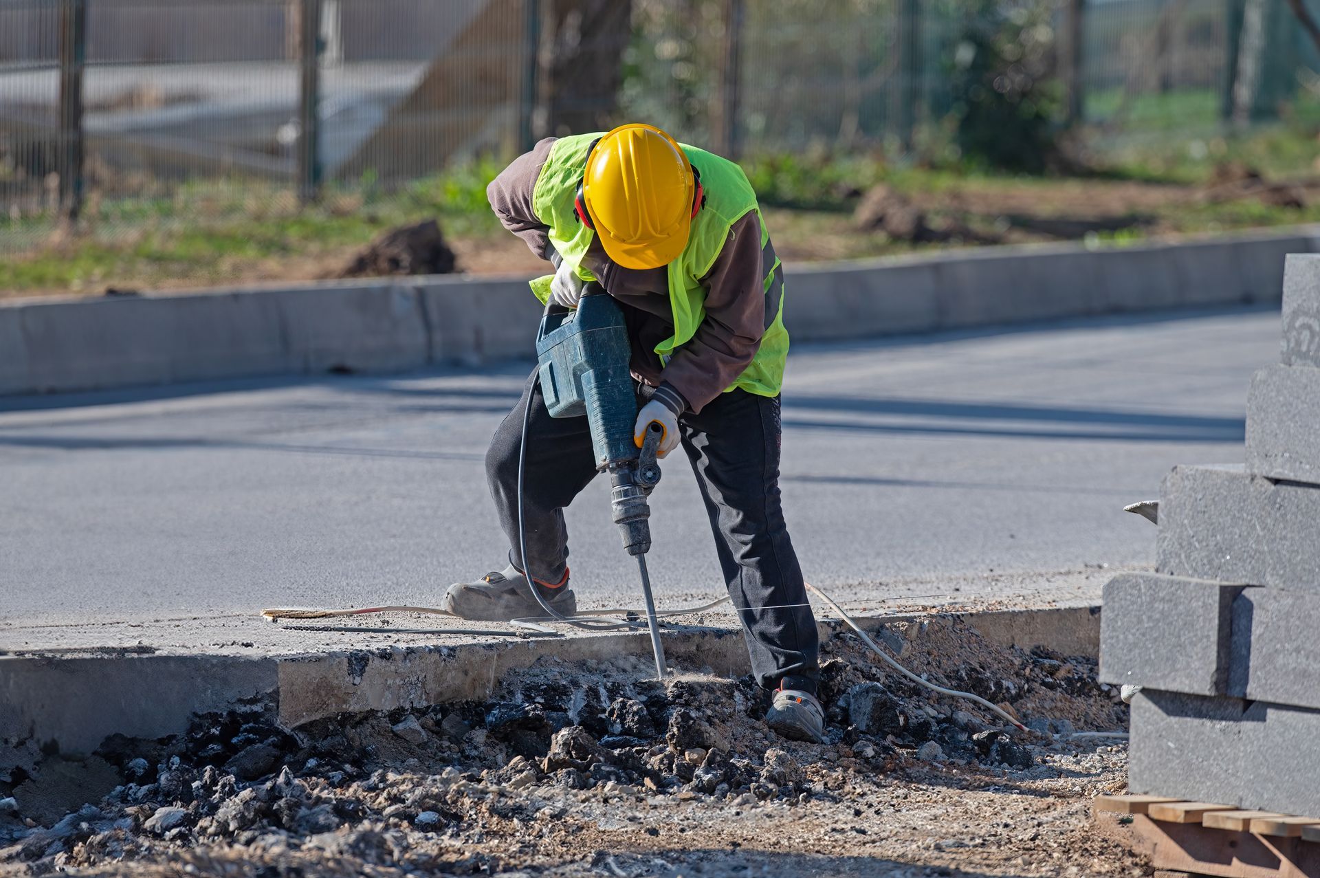 A construction worker is using a hammer to drill a hole in the ground.