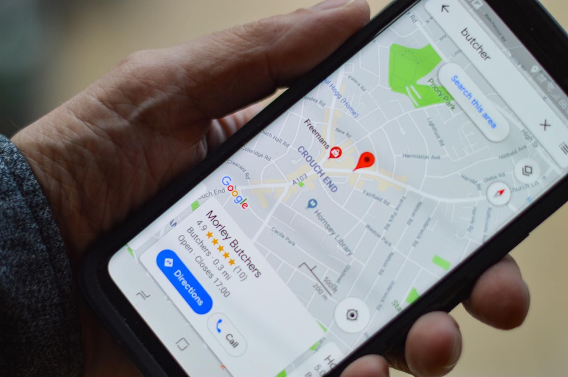 Hand holding a smartphone showing a map with red location pins and directions