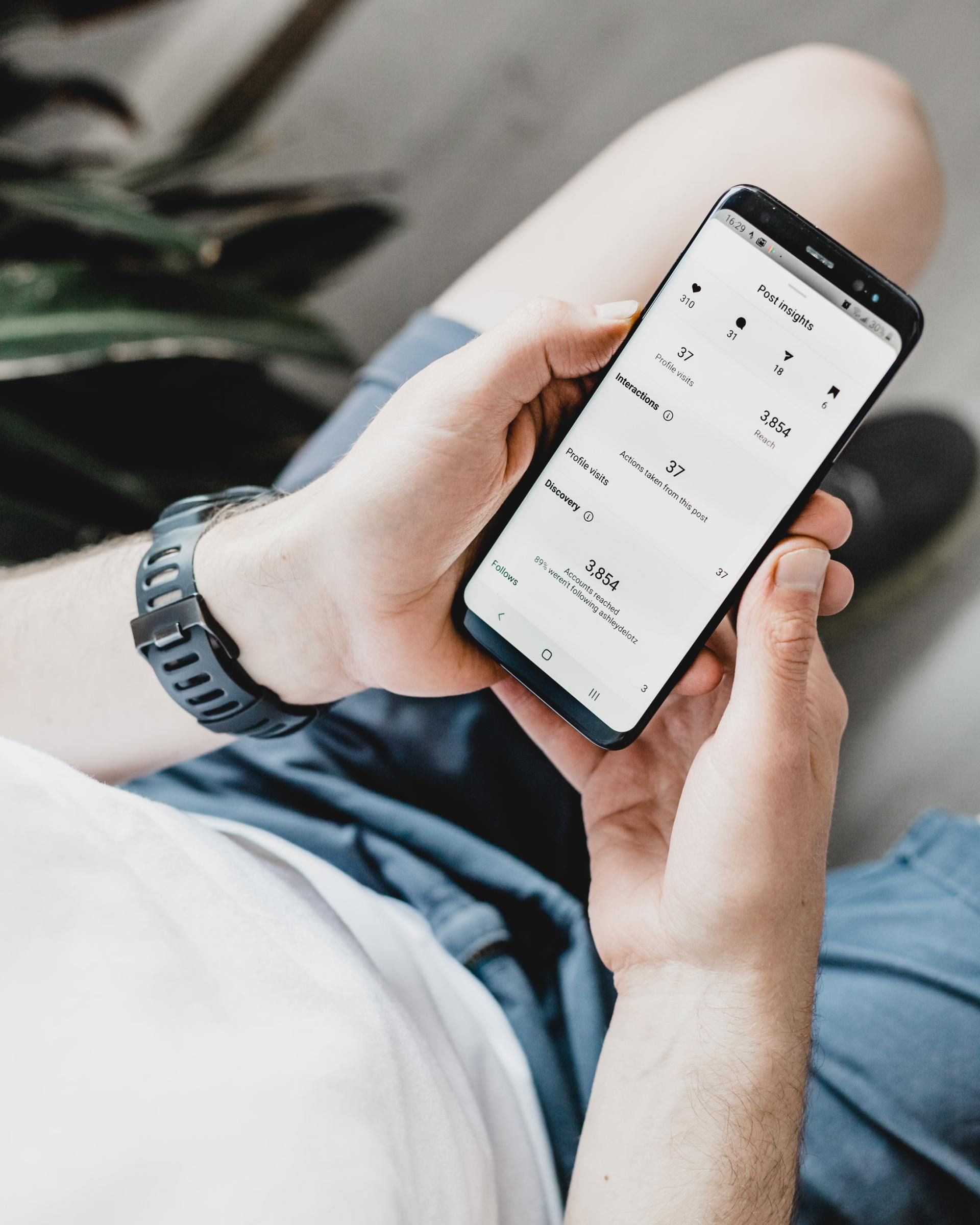 Person holding a smartphone while sitting on a couch and scrolling a white-screen app