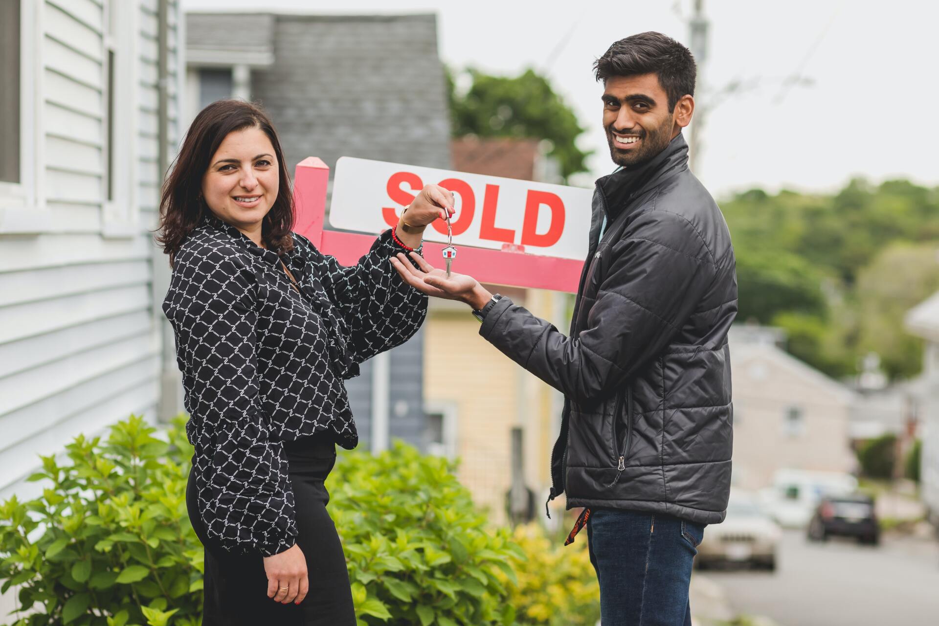 A woman and a man hold keys together in front of a