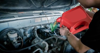 A man is pouring oil into a car engine.