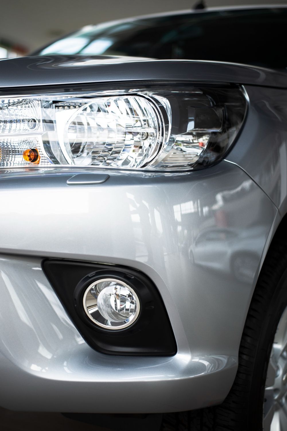 A close up of the front of a silver car in a showroom.