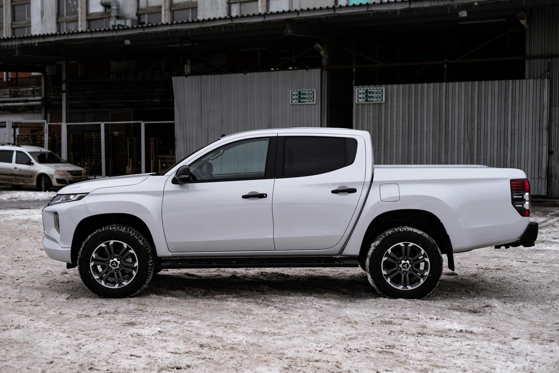 A white pickup truck is parked in the snow in front of a building.