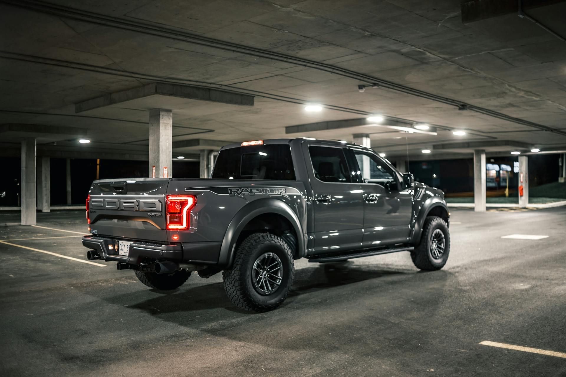 A ford raptor is parked in a parking garage at night.