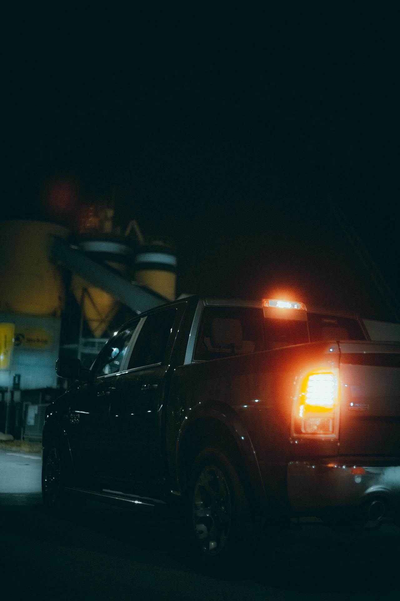 A truck is parked in a parking lot at night with its lights on.